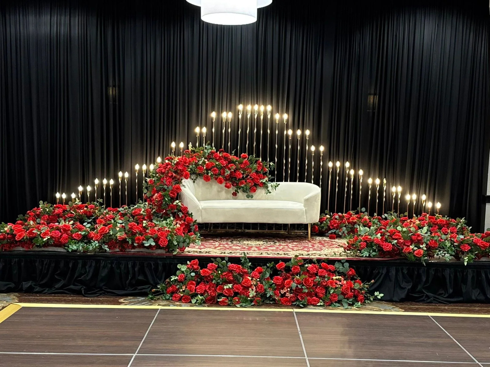 A White Roses Events decor scene with red roses, candlelight and a white lounge